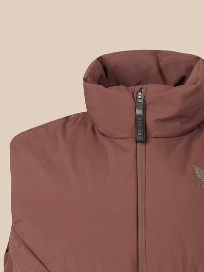 Close-up of a brown insulated jacket with a high stand-up collar, front zipper, and a small wing logo on the chest, shown against a plain beige background.