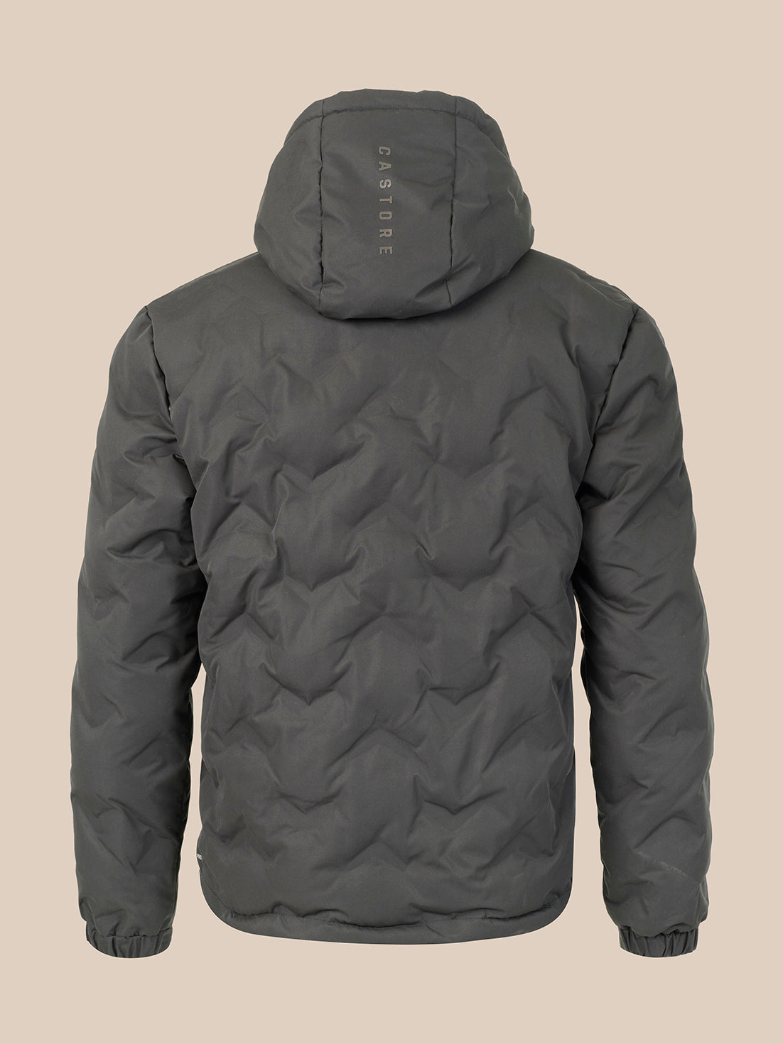 A dark gray hooded puffer jacket shown from the back, featuring a vertical 'CASTORE' logo printed on the back of the hood, set against a solid beige background.
