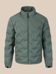 A sage green quilted puffer jacket with a stand-up collar and front zipper, featuring a small embroidered wing logo on the left chest, displayed against a solid beige background.