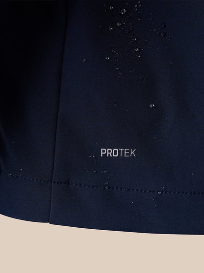 Close-up of a dark navy fabric surface with water droplets beaded on it and the word PROTEK printed near the center, set against a light beige background.