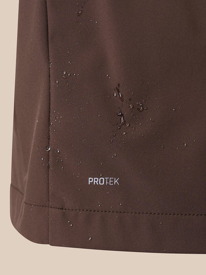 Close-up of a dark brown waterproof fabric surface with water droplets beading on it and the word PROTEK printed near the bottom.