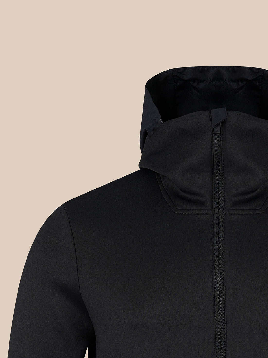 Close-up of a black hooded jacket with a full front zipper, shown against a solid beige background.
