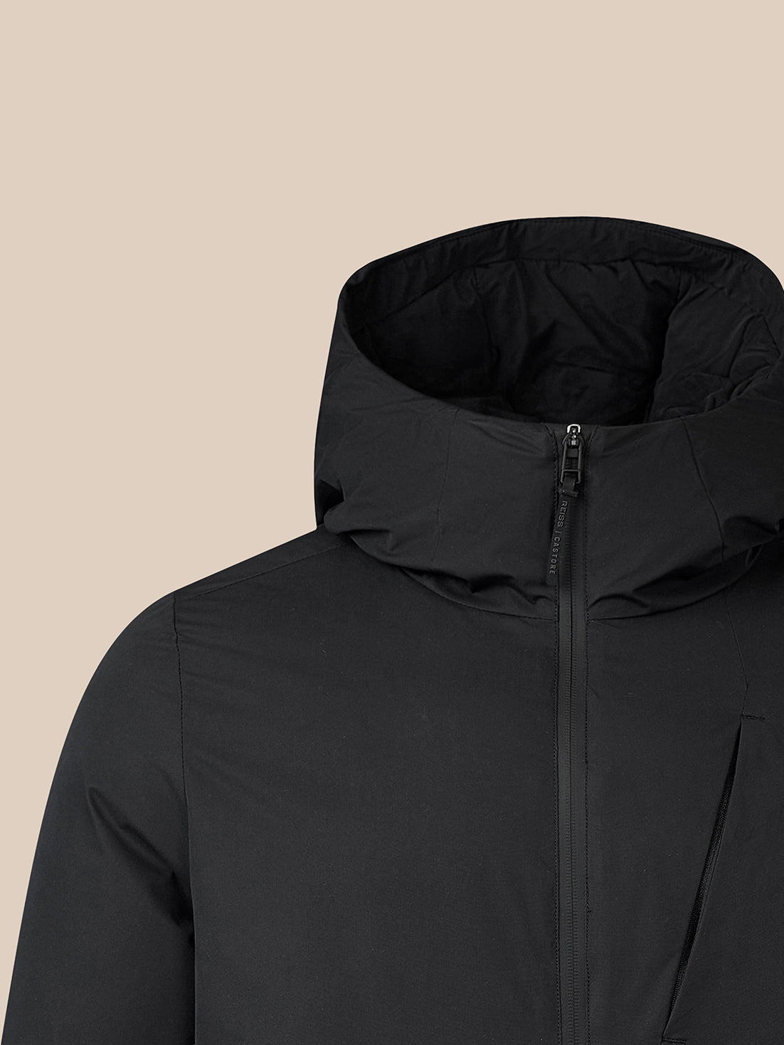 Close-up of a black hooded puffer jacket with a high collar and front zipper, shown against a solid beige background.