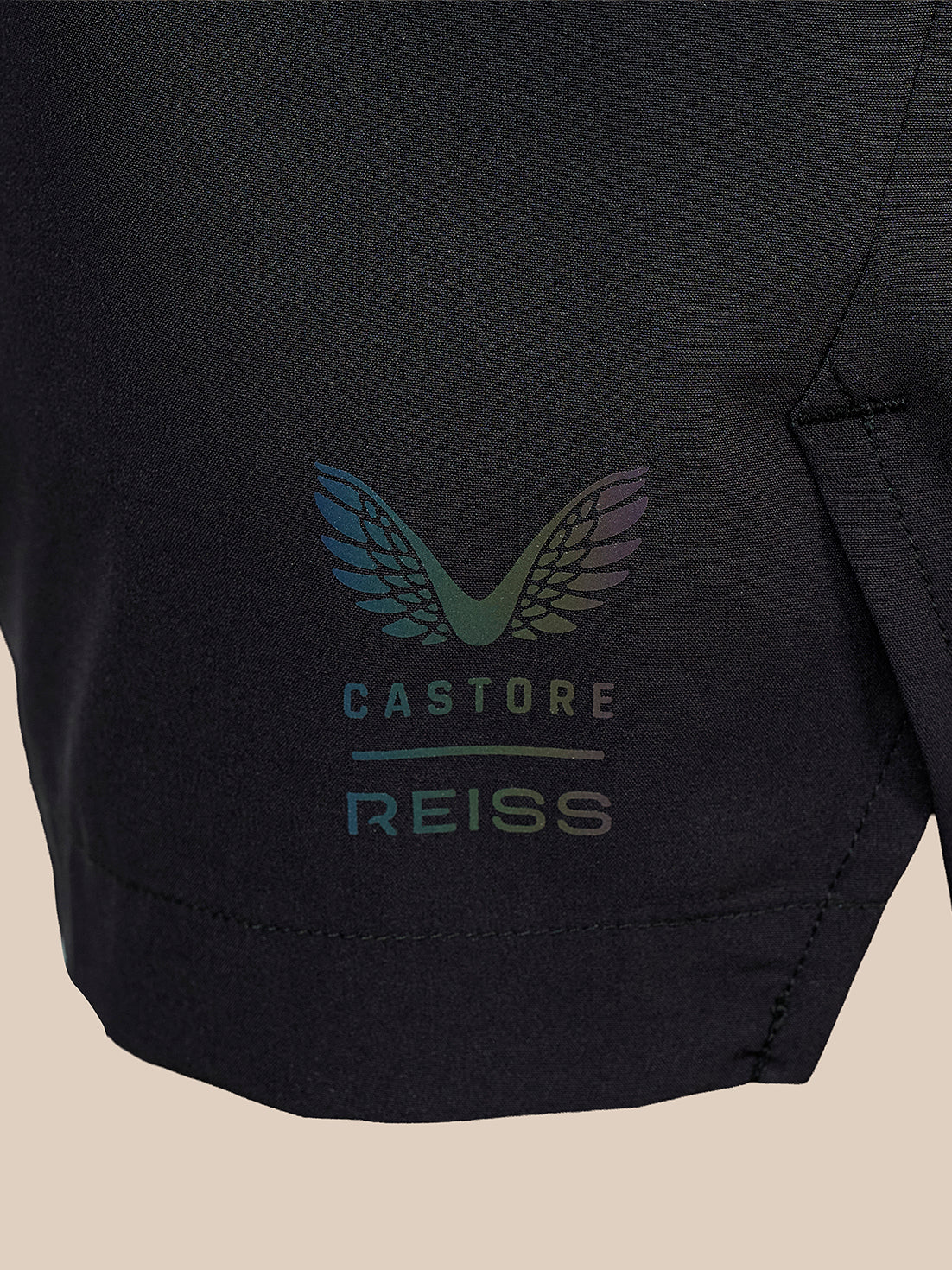 Close-up of a black athletic garment featuring a colorful winged logo and the text 'CASTORE REISS' in a subtle iridescent print.