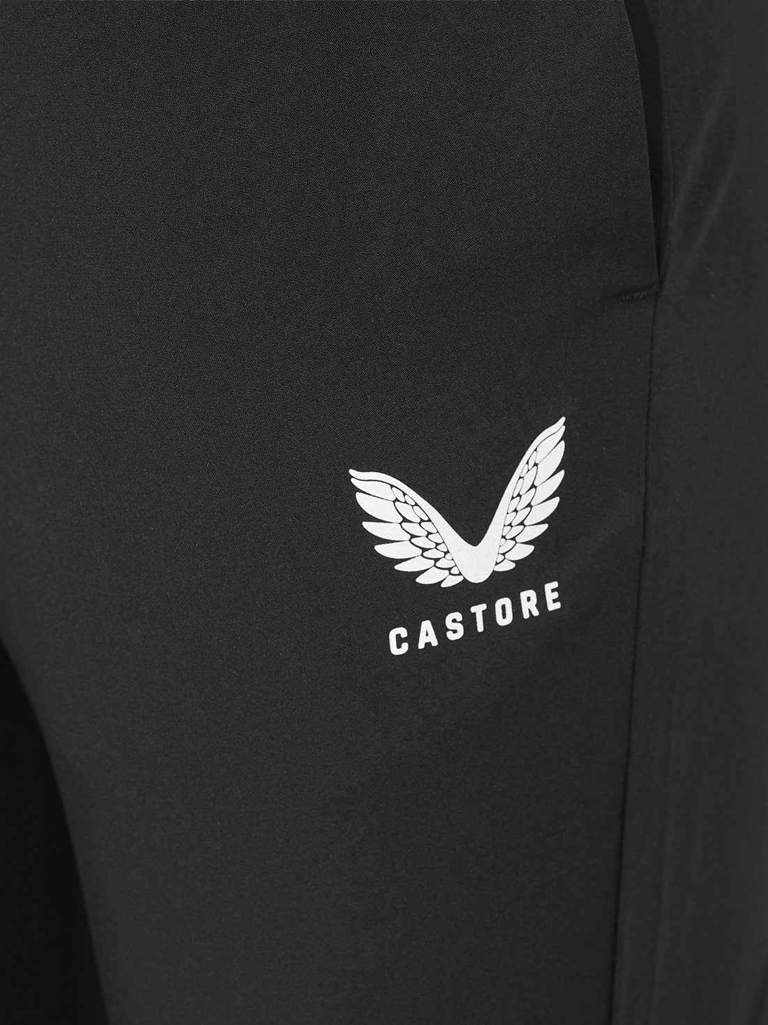 Close-up of a black garment featuring a white Castore wing logo and brand name printed on the chest.