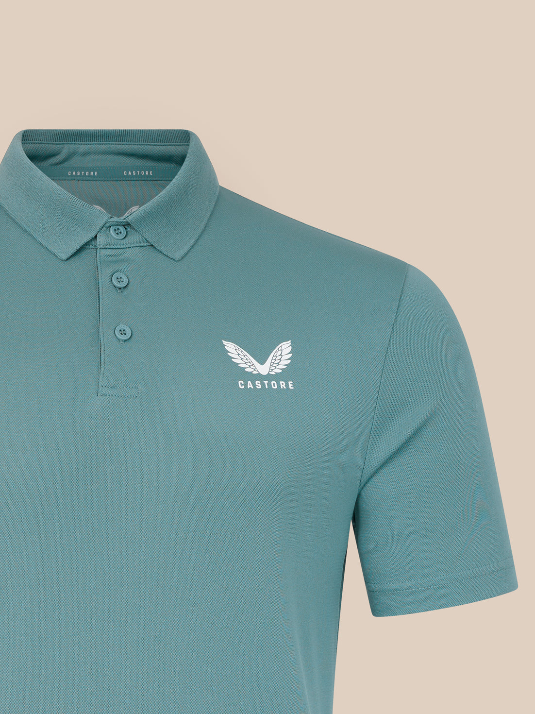 Teal polo shirt with a white logo on a beige background