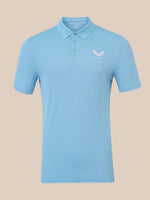 A light blue short-sleeve polo shirt with a three-button placket and a small white wing logo on the left chest, displayed on a solid beige background.