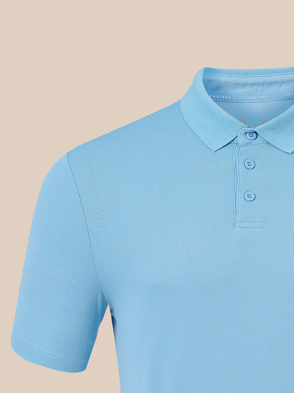 A close-up of a light blue short-sleeve polo shirt on a mannequin or torso form, showing the collar, three-button placket, and ribbed fabric against a solid beige background.