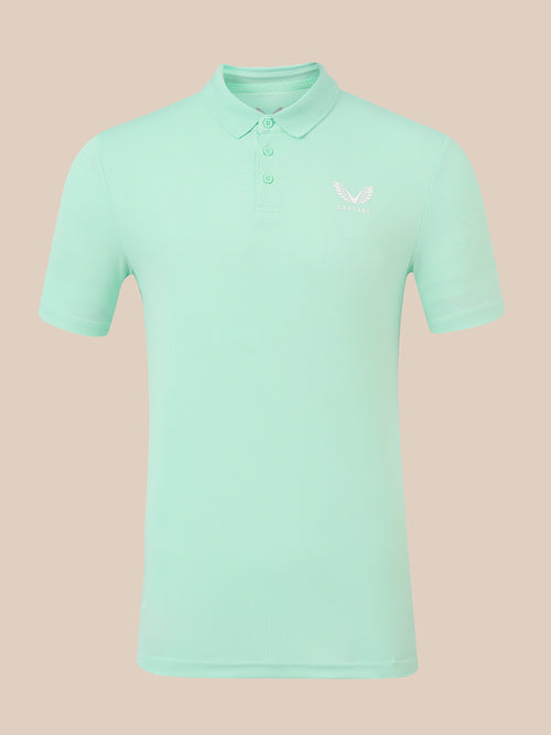 A mint green short-sleeve polo shirt with a small white embroidered logo on the left chest, displayed on a solid beige background.