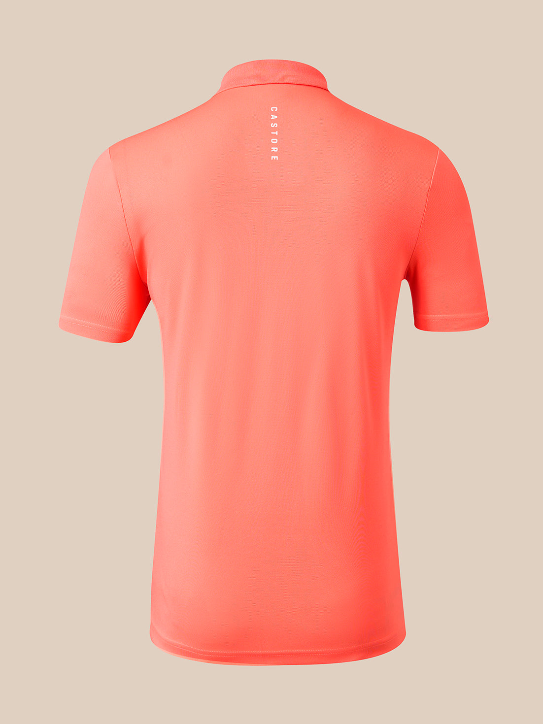 A coral pink short-sleeve polo shirt shown from the back, featuring a vertical white 'CASTORE' logo printed on the upper back, set against a solid beige background.