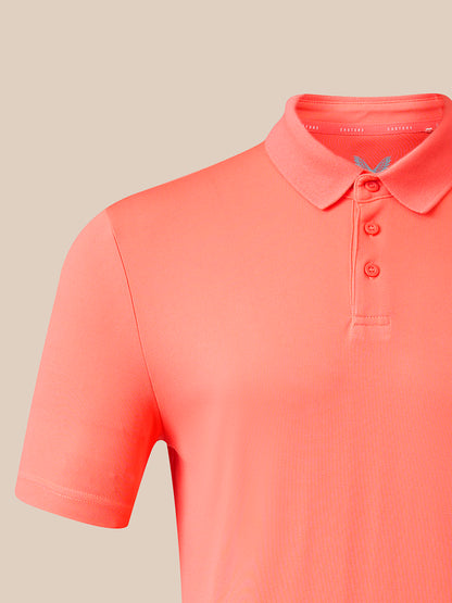 A close-up of a coral pink short-sleeve polo shirt on a neutral beige background.