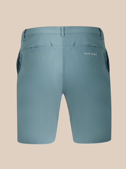 Back view of a pair of Castore blue-gray athletic shorts on a solid beige background.