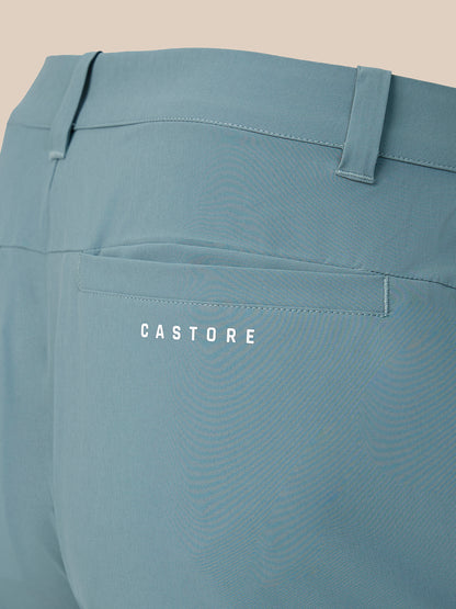 Close-up of the back waistband and pocket area of dusty blue trousers, featuring a back pocket with the brand name 'CASTORE' printed in white.