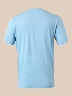 A light blue short-sleeve crewneck t-shirt shown from the back, displayed on a solid beige background.