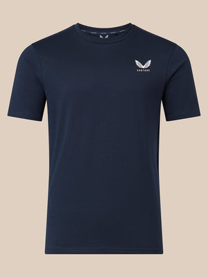 A navy blue short-sleeve crewneck t-shirt with a small white embroidered wing logo and the word 'CASTORE' on the left chest, displayed against a solid beige background.