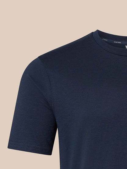 Close-up of a black short-sleeve crewneck t-shirt on a light beige background, showing the inner collar label with the brand name CASTORE.