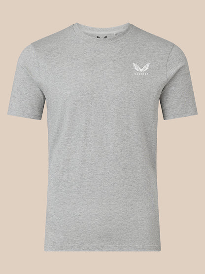 A light gray heather crewneck t-shirt with a small white winged logo on the left chest, displayed on a solid beige background.