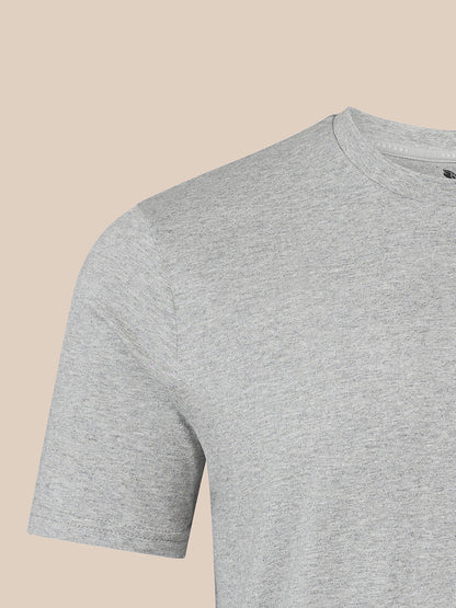 A close-up of a light gray heather crew-neck t-shirt on a solid beige background.