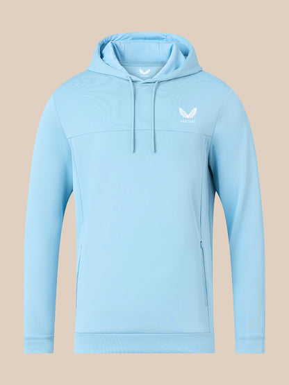 A light blue athletic pullover hoodie with a white winged logo on the left chest, displayed on a solid beige background.