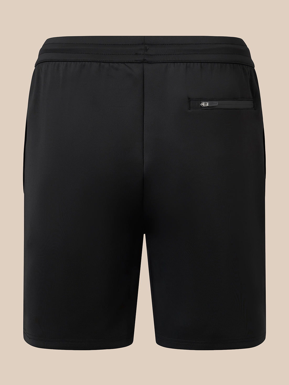Black athletic shorts with an elastic waistband and a zippered side pocket, shown from the back on a solid beige background.