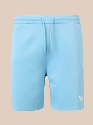 Light blue athletic shorts with a drawstring waist and a small white wing logo on the lower left leg, shown against a solid beige background.