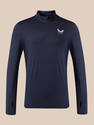 A navy blue long-sleeve quarter-zip athletic pullover with a white wing logo and the word 'Castore' on the left chest, displayed against a solid beige background.
