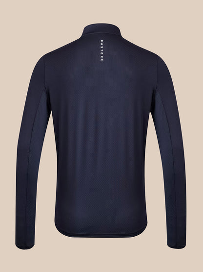 A dark navy long-sleeve athletic top shown from the back, featuring a high collar and a small vertical white brand logo on the upper back, set against a solid beige background.