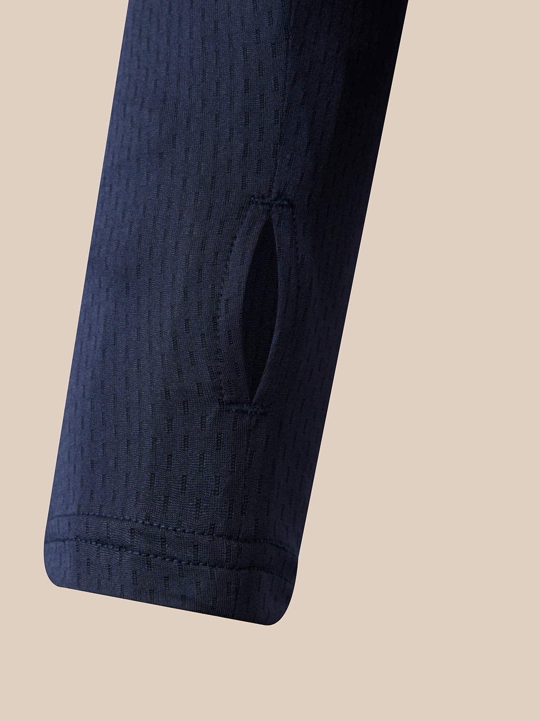 Close-up of a dark navy textured sleeve with a vertical slit detail, set against a solid beige background.