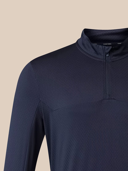 Close-up of a dark navy ribbed long-sleeve quarter-zip performance top on a model, showing the collar and upper chest against a solid beige background.