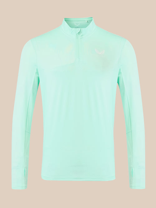 A light mint green long-sleeve athletic quarter-zip pullover with a small white logo on the left chest, displayed on a solid beige background.