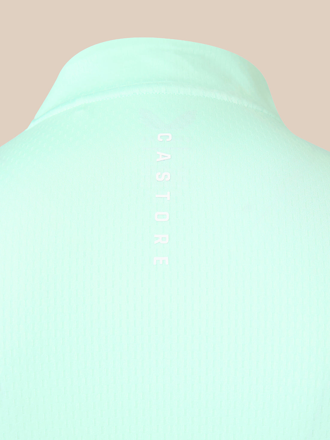 Close-up of a mint green ribbed knit garment, likely a sweater or knit top, showing the back collar and vertical 'CASTORE' branding printed in white on the center.