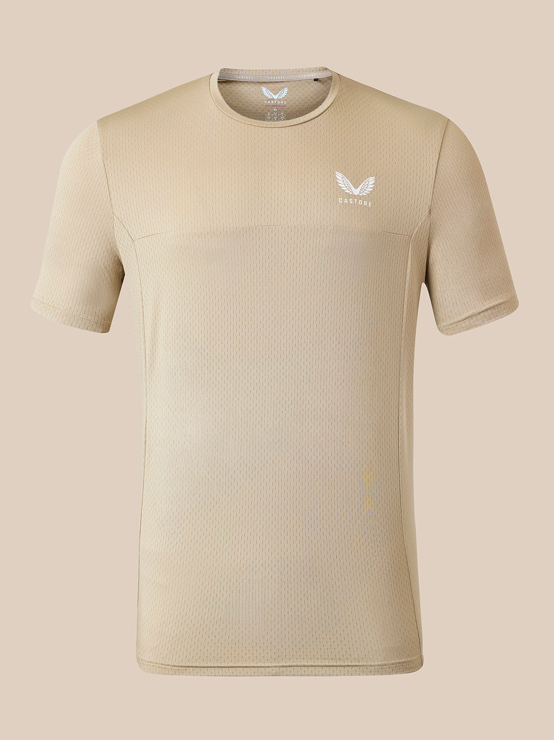 A beige short-sleeve athletic t-shirt with a textured mesh-like fabric, featuring a small white wing logo and the brand name 'CASTORE' on the left chest, displayed against a solid beige background.