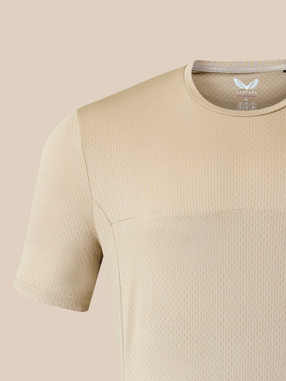 Close-up of a beige short-sleeve athletic top with a textured waffle knit fabric and a visible inner neck label reading CASTORE.