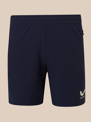 Navy blue athletic shorts with an elastic waistband and a small white embroidered logo on the lower left leg, shown against a solid beige background.