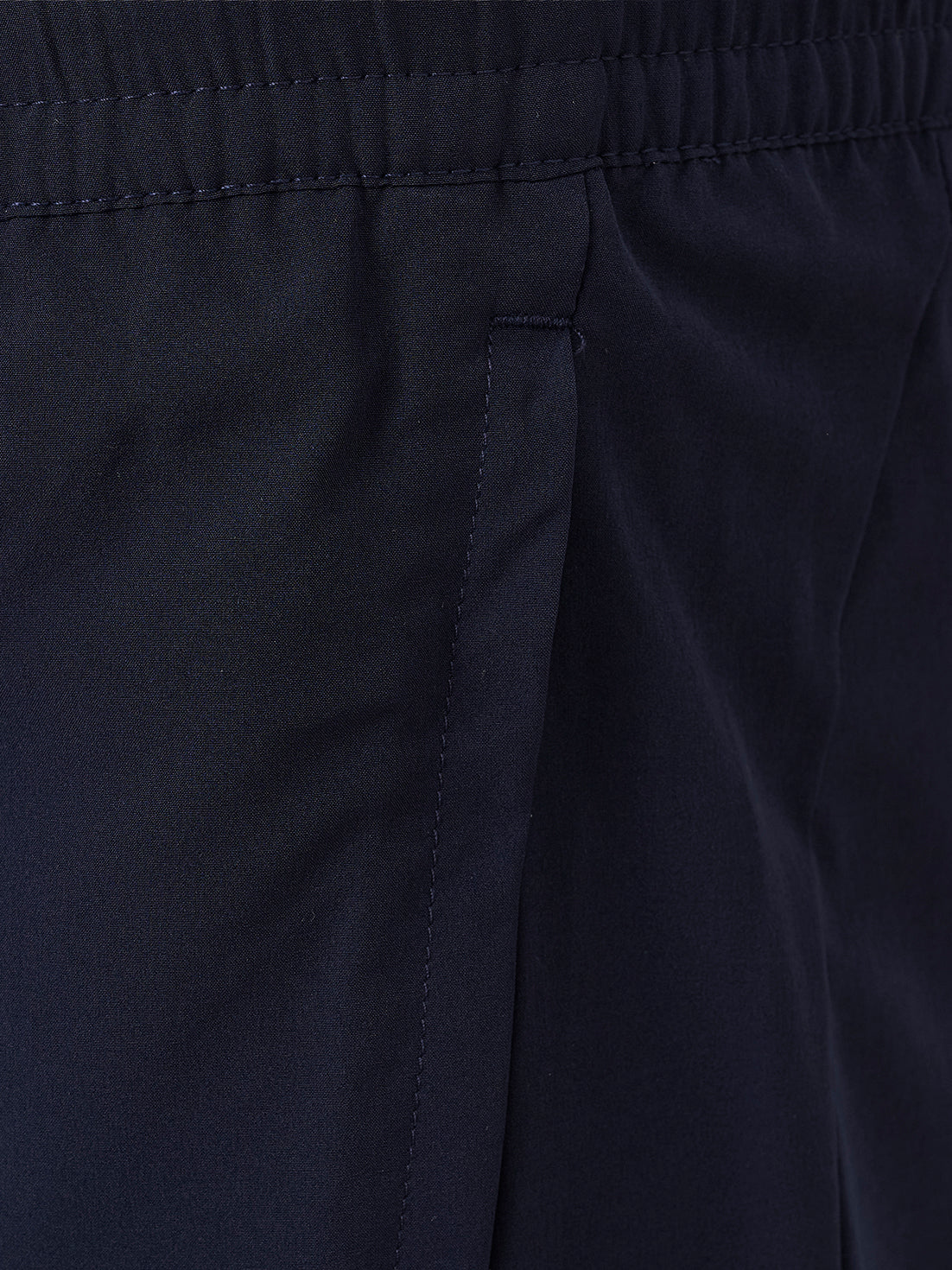 Close-up of dark navy fabric with an elastic waistband and a vertical seam detail.