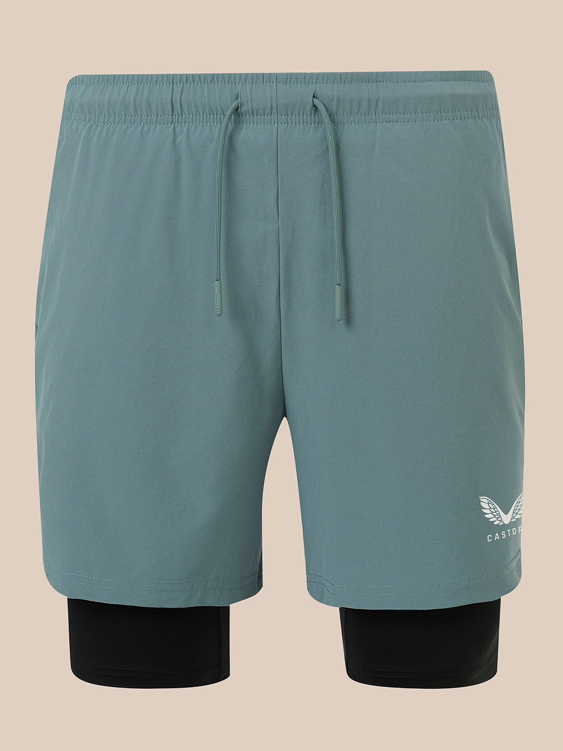 A pair of men's athletic shorts in a muted teal-blue color, featuring a matching drawstring waist and a black inner layer visible at the legs. A small white embroidered wing logo with 'CASTORE' text is on the lower left leg.