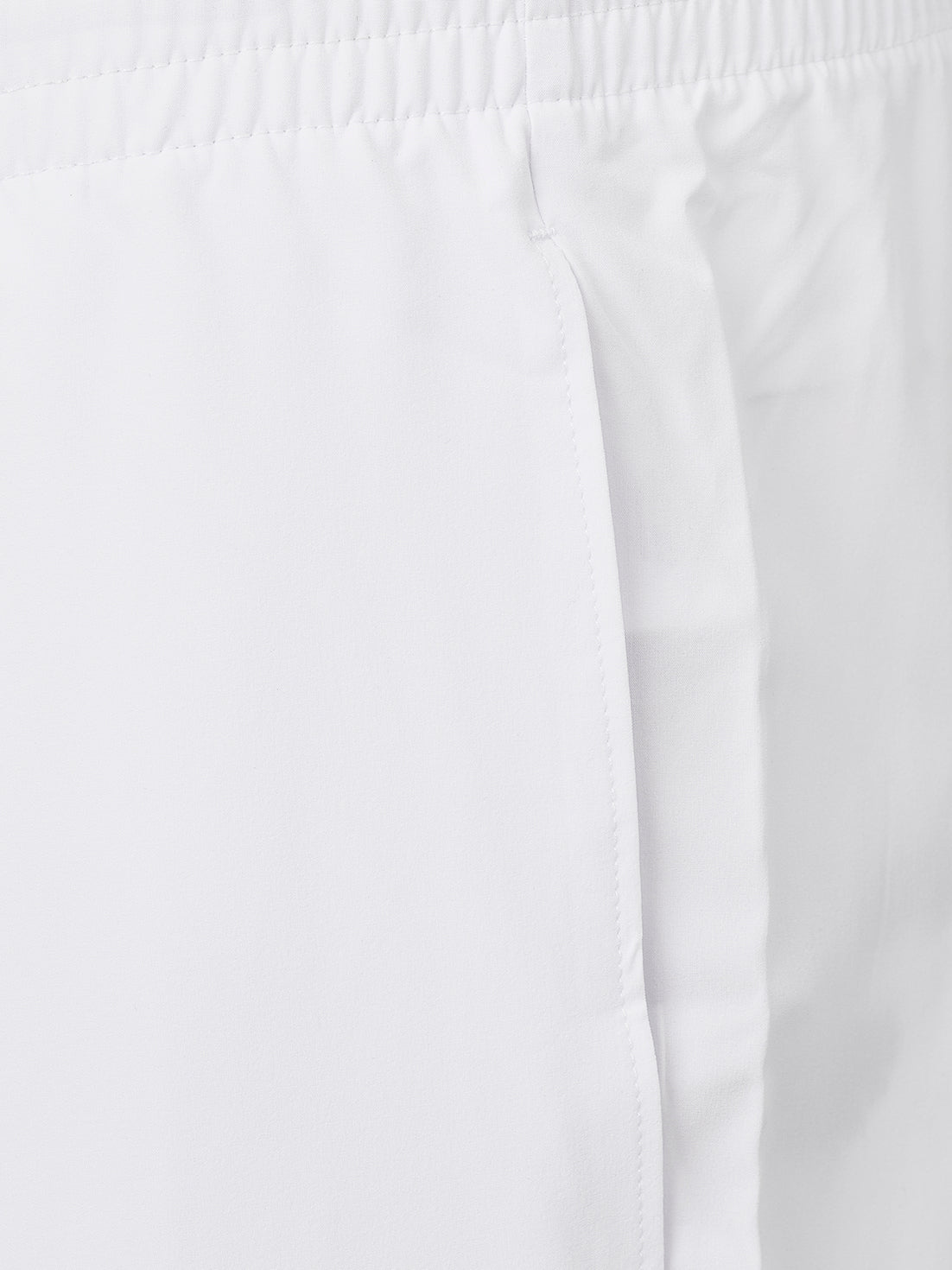 Close-up of white fabric with an elastic waistband and side seam detail.