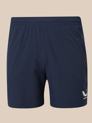 Navy blue athletic shorts with an elastic waistband and a small white winged logo on the lower left leg, displayed against a solid beige background.