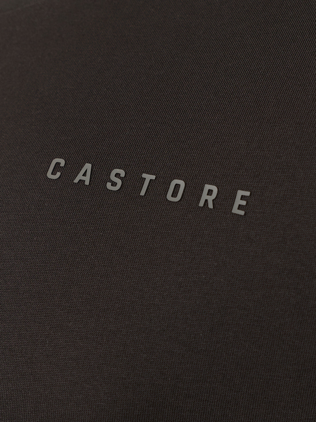 Close-up of a dark charcoal gray textured fabric with the brand name 'CASTORE' printed in a light gray sans-serif font across the center.