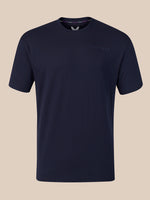 A dark navy blue crew-neck t-shirt with a subtle tonal embroidered logo on the left chest, displayed against a solid beige background.