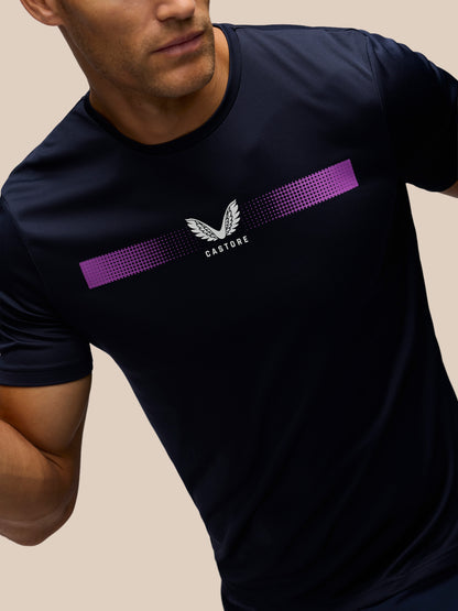 A close-up of a man wearing a navy blue athletic t-shirt with a purple and white chest graphic featuring the brand name 'CASTORE'.