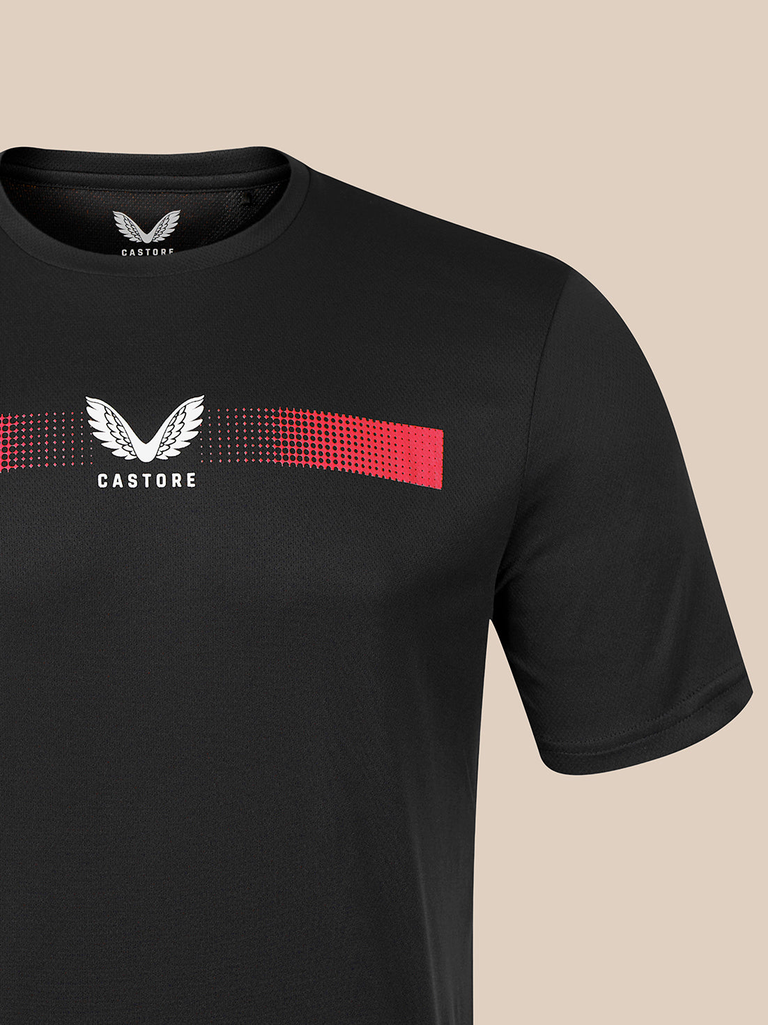 A close-up of a black Castore short-sleeve t-shirt featuring a white winged logo and the brand name 'CASTORE' printed on the chest, with a red and black dotted gradient stripe running horizontally behind the logo.