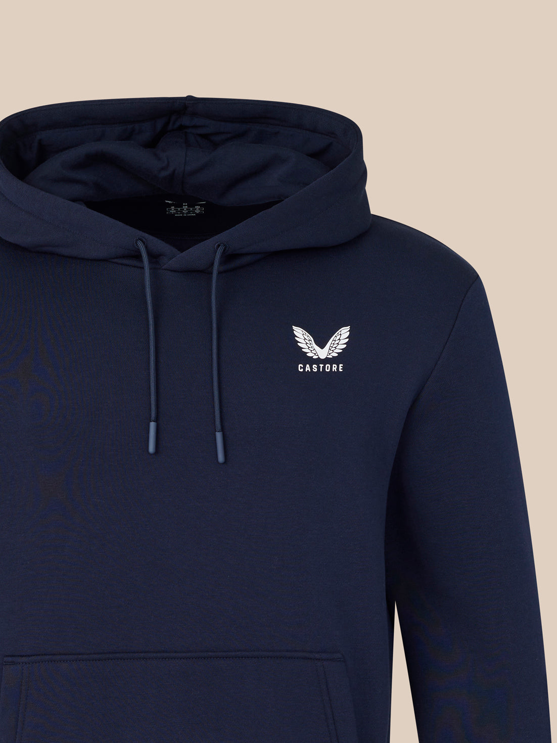 Navy hoodie with a logo on the chest against a beige background