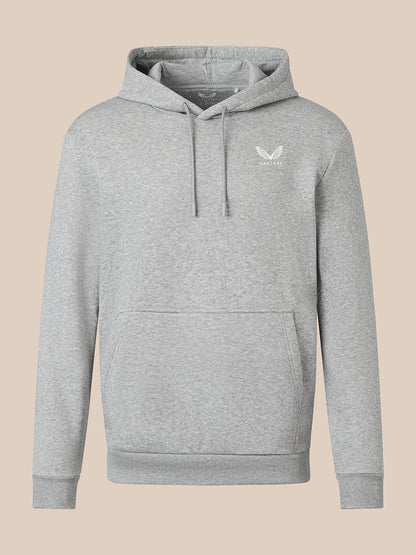 A light heather gray pullover hoodie with a small white embroidered winged logo on the left chest, displayed against a solid beige background.