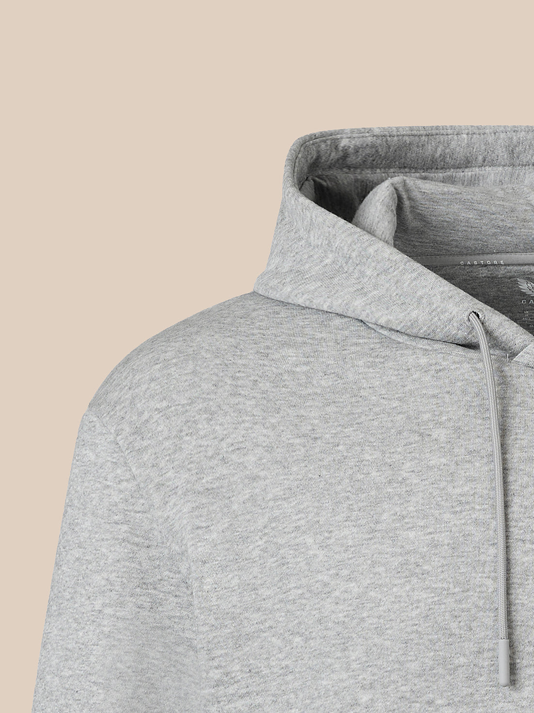 Close-up of a light heather gray hoodie showing the hood lining and drawstring against a solid beige background.