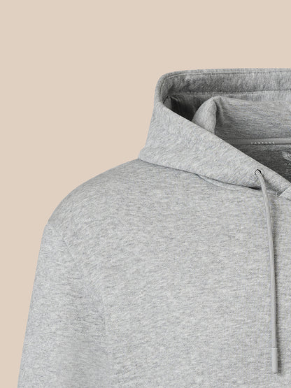 Close-up of a light heather gray hoodie showing the hood lining and drawstring against a solid beige background.