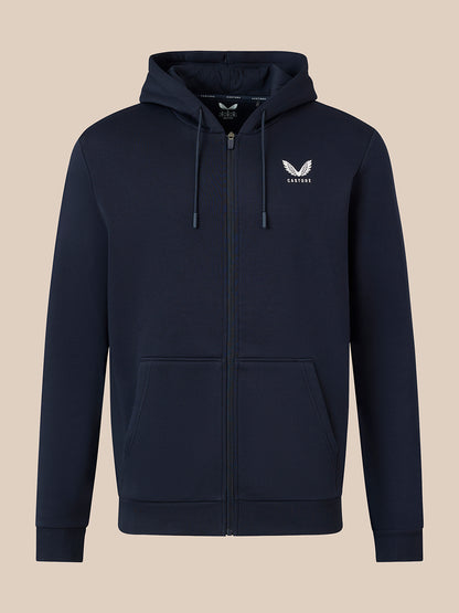 A navy blue zip-up hoodie with a white embroidered winged logo on the left chest, displayed on a solid beige background.