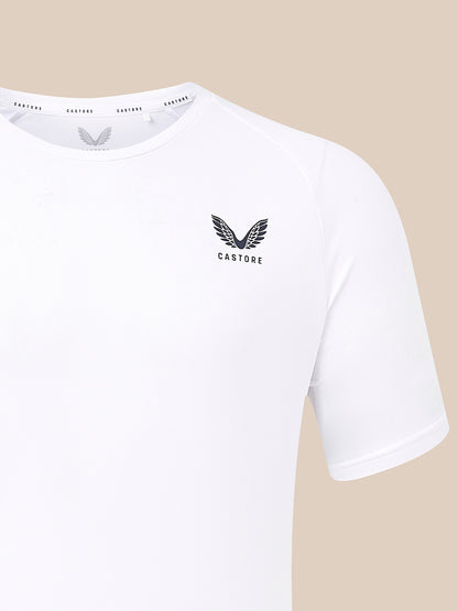 White short-sleeve athletic t-shirt with a black winged Castore logo on the left chest, shown against a solid beige background.