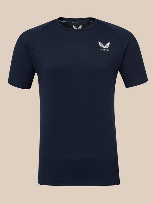 A dark navy blue short-sleeve athletic t-shirt with a white winged logo and the brand name 'CASTORE' printed on the left chest, displayed against a solid beige background.