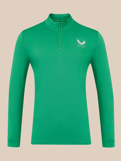 A green long-sleeve quarter-zip pullover with a small white wing logo and the brand name 'Castore' on the left chest, displayed on a solid beige background.
